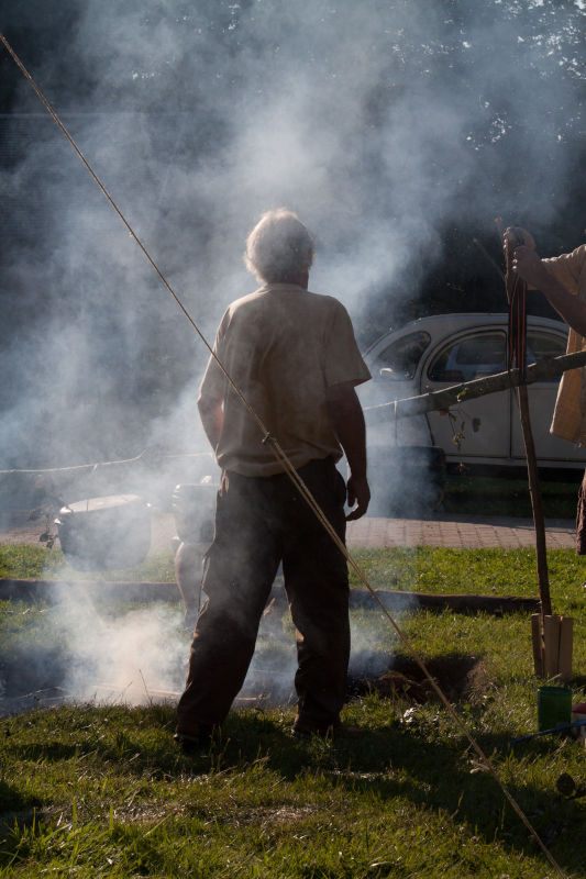 Grottentreffen 2012 in Reclere, Toni im Rauch der Feuerstelle stehend und die Kochjtöpfe betrachtend